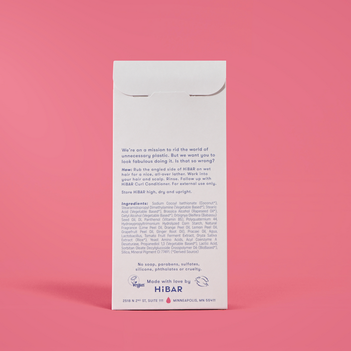 Photo of the back of the packaging of the shampoo bar on a red background.