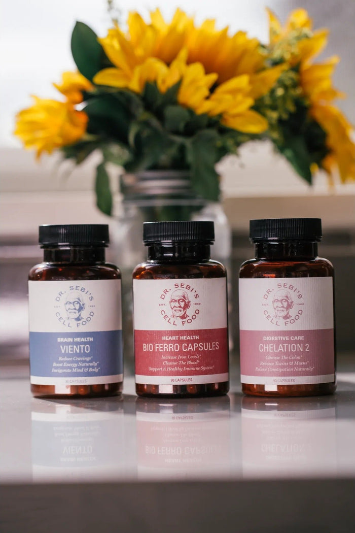 Three Dr. Sebi Cell Food supplement bottles (Viento, Bio Ferro Capsules, Chelation 2) displayed with sunflowers in backgro...