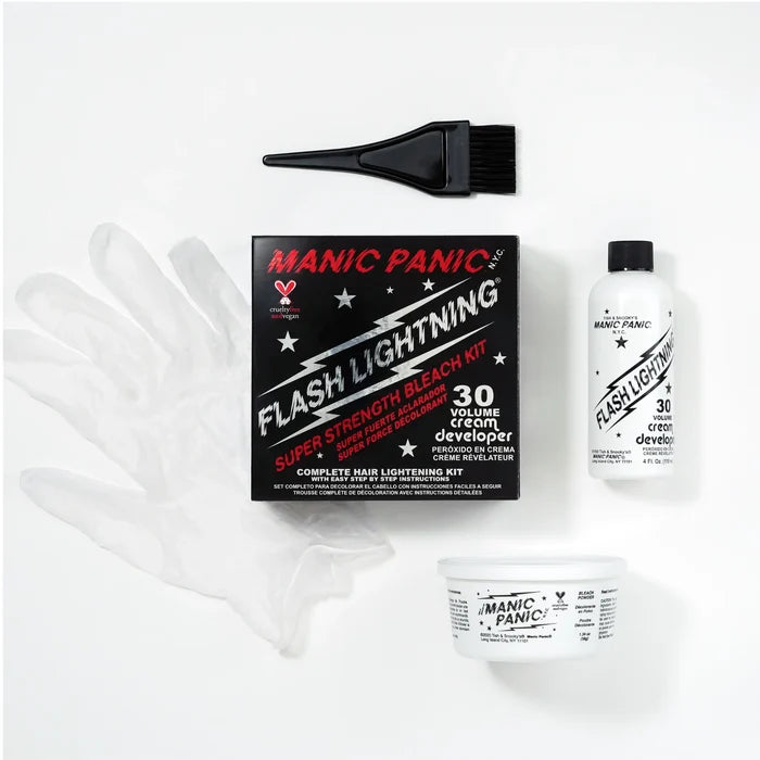 Manic Panic Flash Lighting kit laid out on a white background, including a black applicator brush, a black retail box, a clear protective glove, a white developer bottle, and a white cream container.