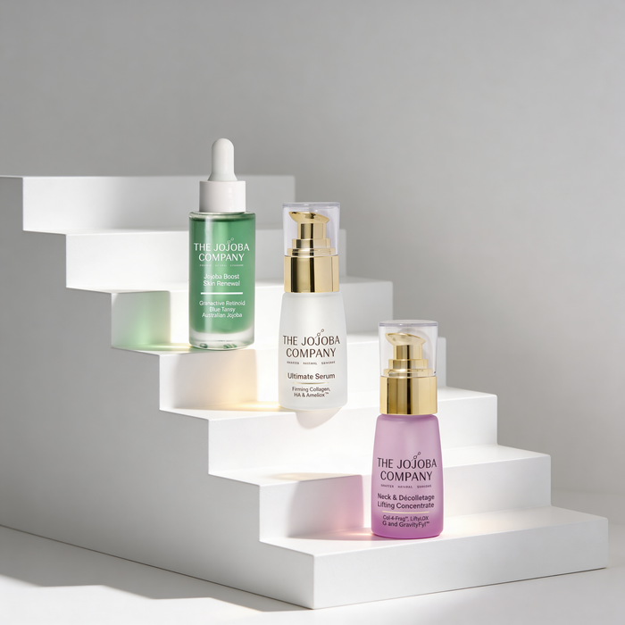 Skincare products from The Jojoba Company on a white platform with a gray background