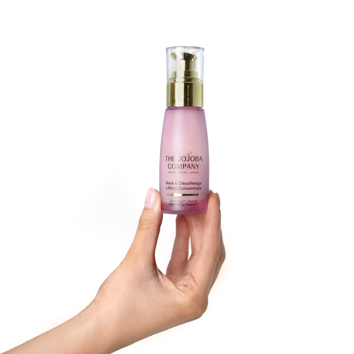 Hand holding a pink skincare bottle with gold cap on a white background
