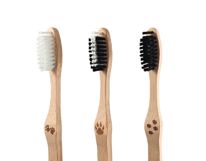 Three bamboo toothbrushes with white and black bristles arranged in a row