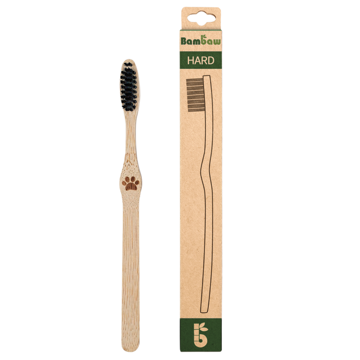 Bambaw bamboo toothbrush with black bristles beside its tall kraft packaging labeled HARD