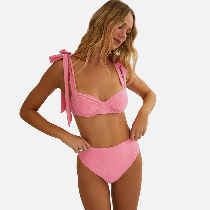 Woman wearing a pink bikini with a white background