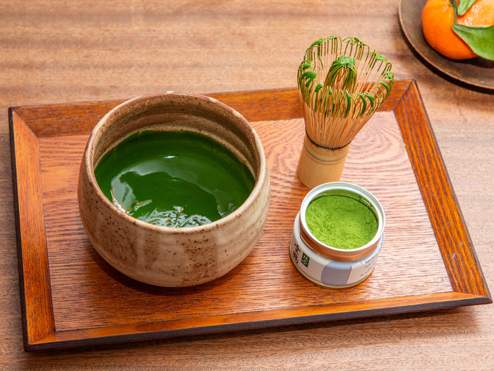 Matcha green tea set with bowl, whisk, and container on a wooden tray. Koicha