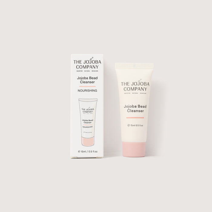 Jojoba bead cleanser with packaging from The Jojoba Company on a light gray background