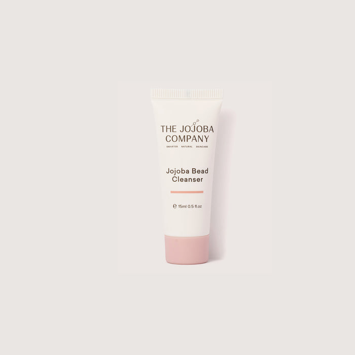 Jojoba bead cleanser bottle with pink cap on a white background